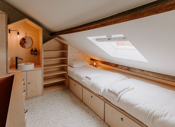 Sfeervolle verlichting naast bed in Jolie Logie, vakantiehuis in Nieuwpoort, West-Vlaanderen, met houten details.