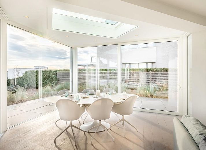 Helles Wohnzimmer des Ferienhauses La Perle in Oostduinkerke, Westflandern, mit moderner Einrichtung und Blick auf die Terrasse.