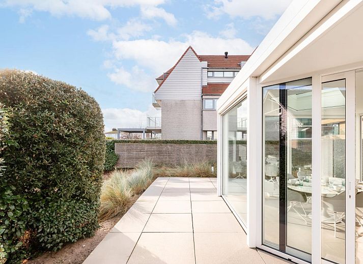 Helles Wohnzimmer des Ferienhauses La Perle in Oostduinkerke, Westflandern, mit moderner Einrichtung und Blick auf die Terrasse.