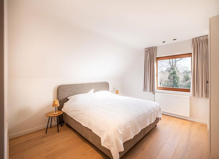 Moderne Kueche im Ferienhaus "Pure Relax" in Oostduinkerke mit heller Einrichtung und Blick auf den Garten in Westflandern, Belgien.