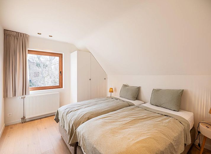 Moderne Kueche im Ferienhaus "Pure Relax" in Oostduinkerke mit heller Einrichtung und Blick auf den Garten in Westflandern, Belgien.