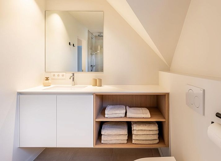 Moderne Kueche im Ferienhaus "Pure Relax" in Oostduinkerke mit heller Einrichtung und Blick auf den Garten in Westflandern, Belgien.