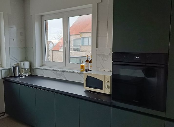 Cozy living room in Papa's Dream vacation home, Oostduinkerke, with large dining table and view of terrace.