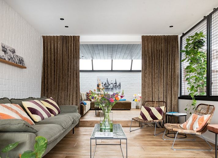 Cozy sitting area in WOWie&Germain vacation home, Oostduinkerke, with plants and colorful cushions.