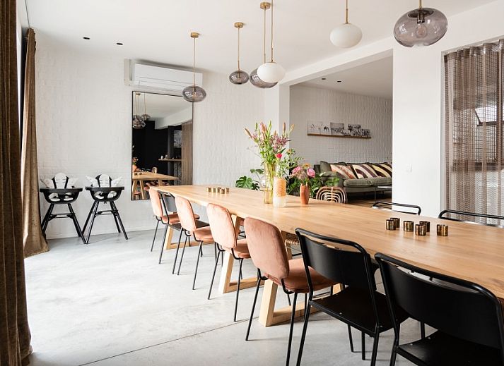 Cozy sitting area in WOWie&Germain vacation home, Oostduinkerke, with plants and colorful cushions.