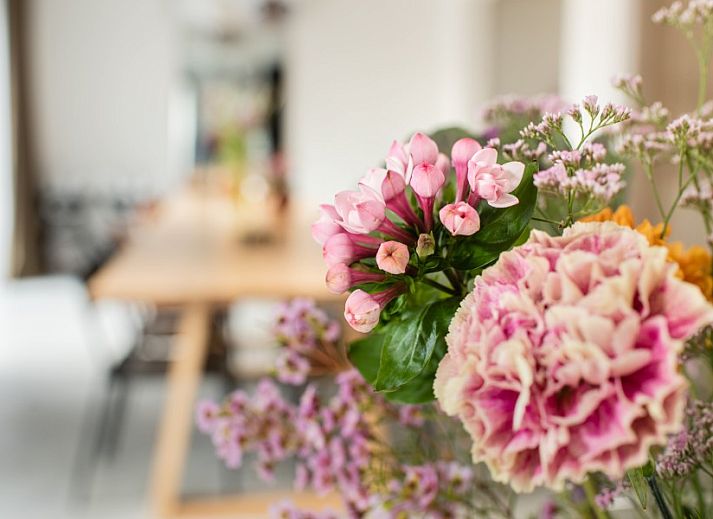Spacious dining room in WOWie&Germain, Oostduinkerke, with long wooden table and atmospheric lighting.