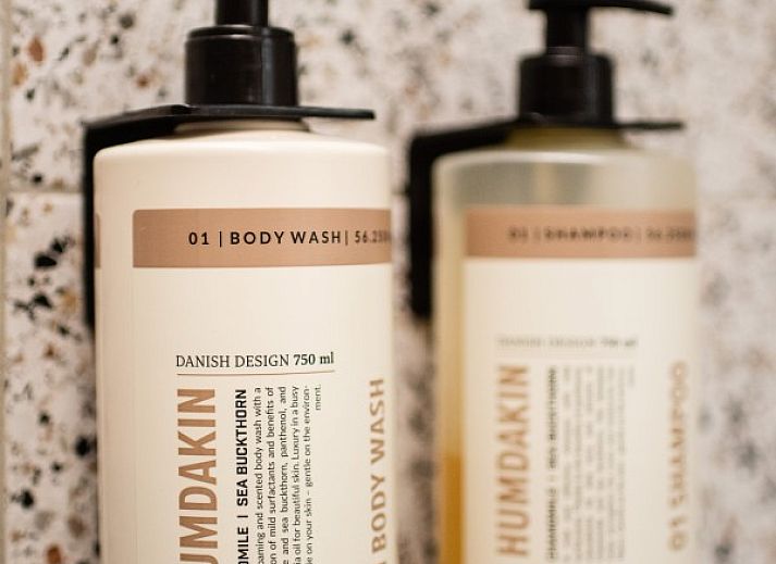 Spacious dining room in WOWie&Germain, Oostduinkerke, with long wooden table and atmospheric lighting.