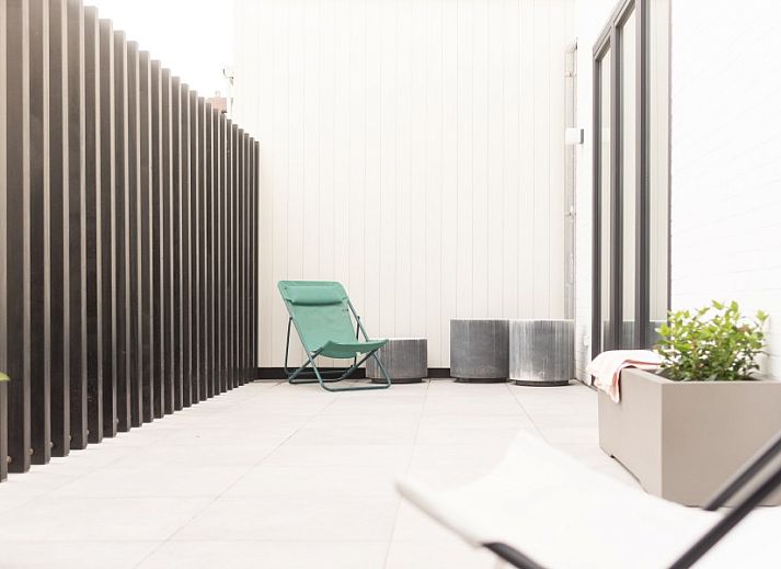 Spacious dining room in WOWie&Germain, Oostduinkerke, with long wooden table and atmospheric lighting.