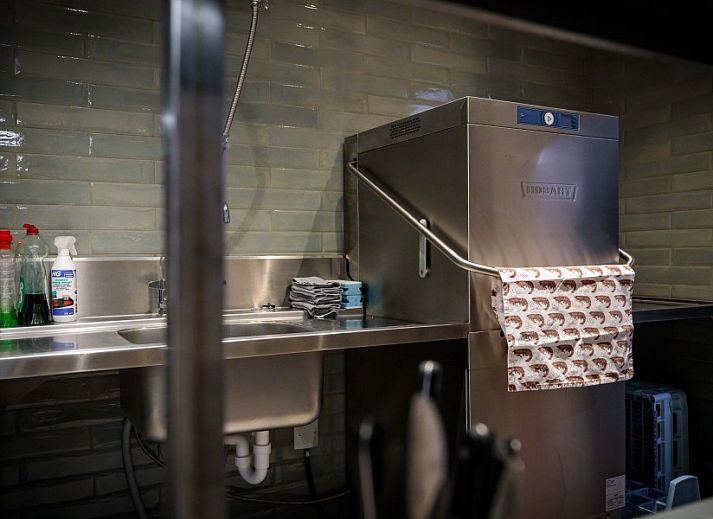 Spacious dining room in WOWie&Germain, Oostduinkerke, with long wooden table and atmospheric lighting.