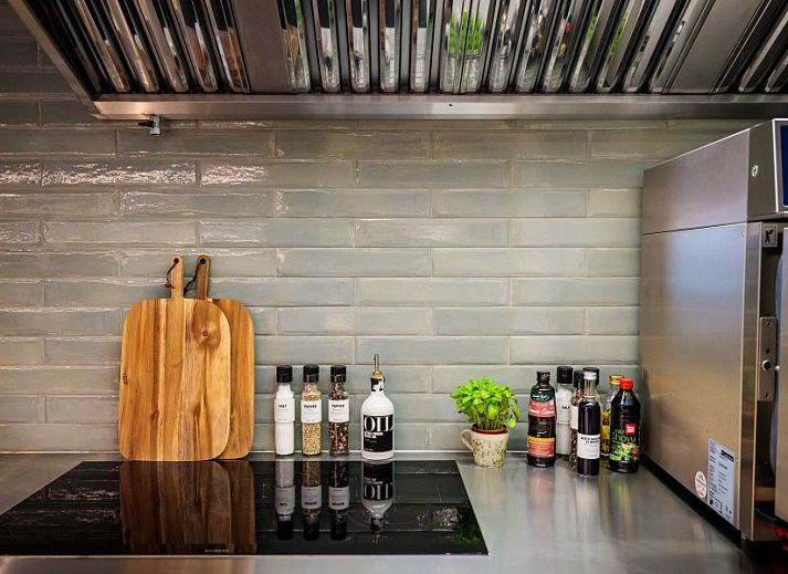 Spacious dining room in WOWie&Germain, Oostduinkerke, with long wooden table and atmospheric lighting.