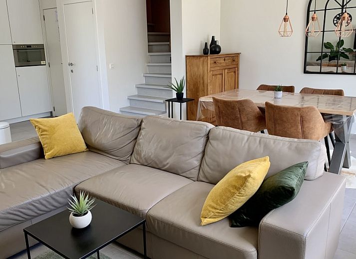 Gemuetliche Terrasse von Het Anker in Oostduinkerke mit Holzsitzen und bunten Blumen.
