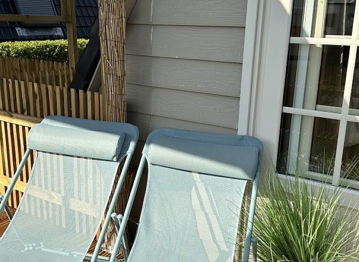 Chalet chez Dune in Oostduinkerke, een charmant vakantiehuis met houten hek en bloeiende tuin in West-Vlaanderen, Belgie.