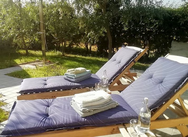 Gemuetlicher Abend auf der Veranda des Ferienhauses in Assenede, Ostflandern, stimmungsvoll beleuchtet mit bequemen Sitzgelegenheiten.