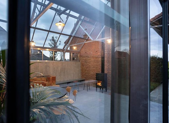 Heller Innenraum eines Ferienhauses in Sint-Pauwels, Belgien, mit Glasdach und gemuetlichem Essbereich.