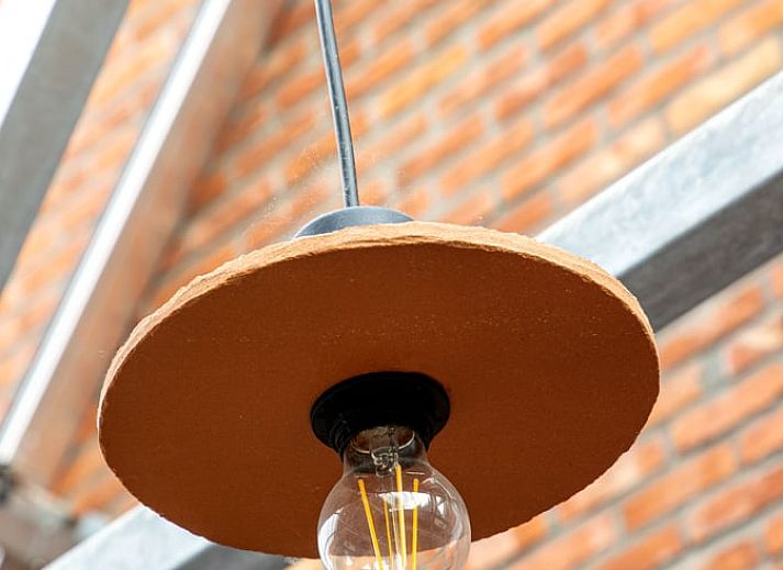 Heller Innenraum eines Ferienhauses in Sint-Pauwels, Belgien, mit Glasdach und gemuetlichem Essbereich.