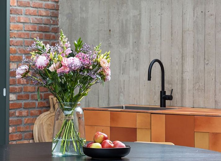 Heller Innenraum eines Ferienhauses in Sint-Pauwels, Belgien, mit Glasdach und gemuetlichem Essbereich.