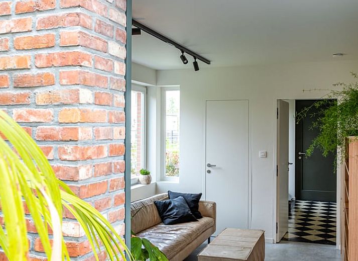 Stilvolles Esszimmer im Ferienhaus in Sint-Pauwels, Ostflandern, mit Holzmoebeln und Betonwaenden.