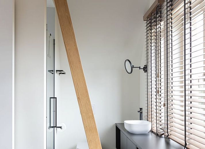 Moderne Kueche eines Ferienhauses in Sint-Pauwels, Belgien, mit schlichtem Design und warmen Farbtoenen.