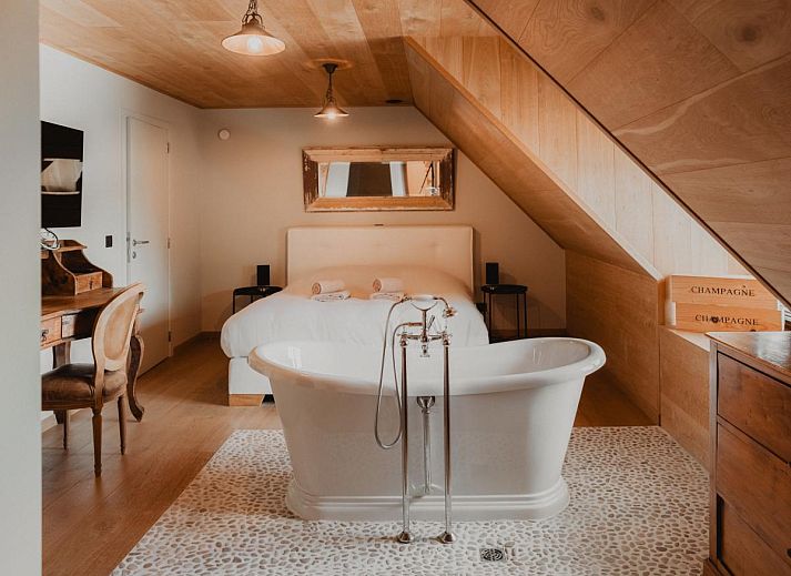 Stijlvolle woonkamer van Villa Noortem, een vakantiehuis in Maldegem, Oost-Vlaanderen, met luxe leren bank en sfeervolle open haard.
