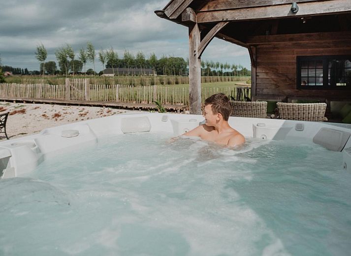 Stijlvolle woonkamer van Villa Noortem, een vakantiehuis in Maldegem, Oost-Vlaanderen, met luxe leren bank en sfeervolle open haard.
