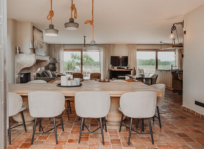 Stijlvolle woonkamer van Villa Noortem, een vakantiehuis in Maldegem, Oost-Vlaanderen, met luxe leren bank en sfeervolle open haard.