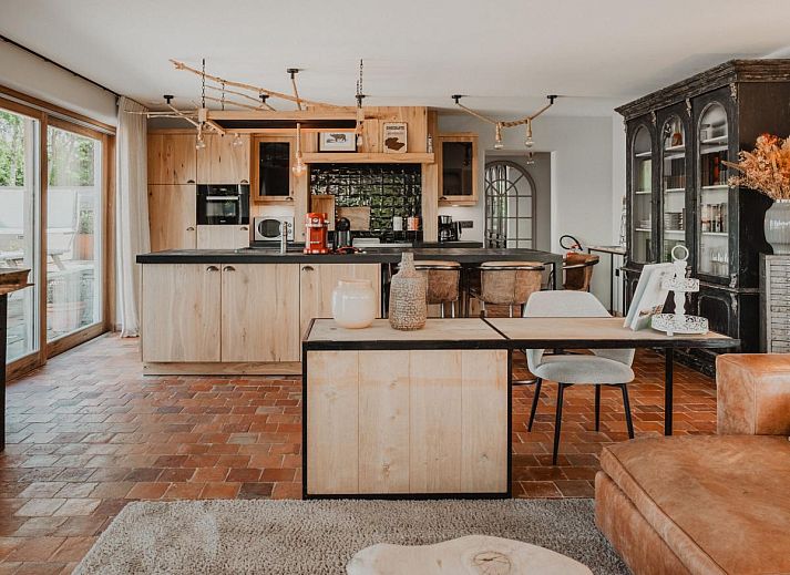 Stijlvolle woonkamer van Villa Noortem, een vakantiehuis in Maldegem, Oost-Vlaanderen, met luxe leren bank en sfeervolle open haard.