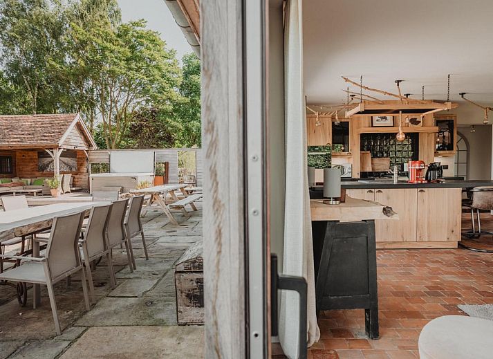 Stijlvolle woonkamer van Villa Noortem, een vakantiehuis in Maldegem, Oost-Vlaanderen, met luxe leren bank en sfeervolle open haard.