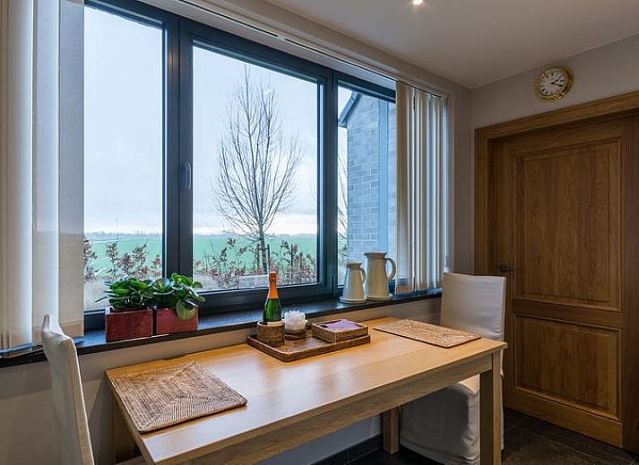 Gemuetliches Wohnzimmer in Cottage in Sint-Laureins, Ferienhaus in Ostflandern, mit bequemer Sitzecke und Blick auf die gruene Landschaft.
