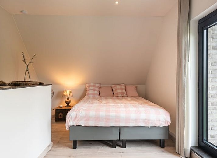 Gemuetliches Wohnzimmer in Cottage in Sint-Laureins, Ferienhaus in Ostflandern, mit bequemer Sitzecke und Blick auf die gruene Landschaft.