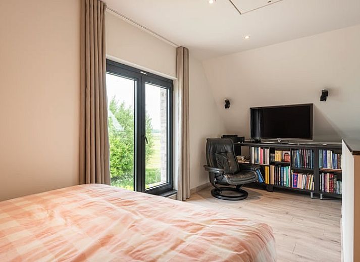 Gemuetliches Wohnzimmer in Cottage in Sint-Laureins, Ferienhaus in Ostflandern, mit bequemer Sitzecke und Blick auf die gruene Landschaft.