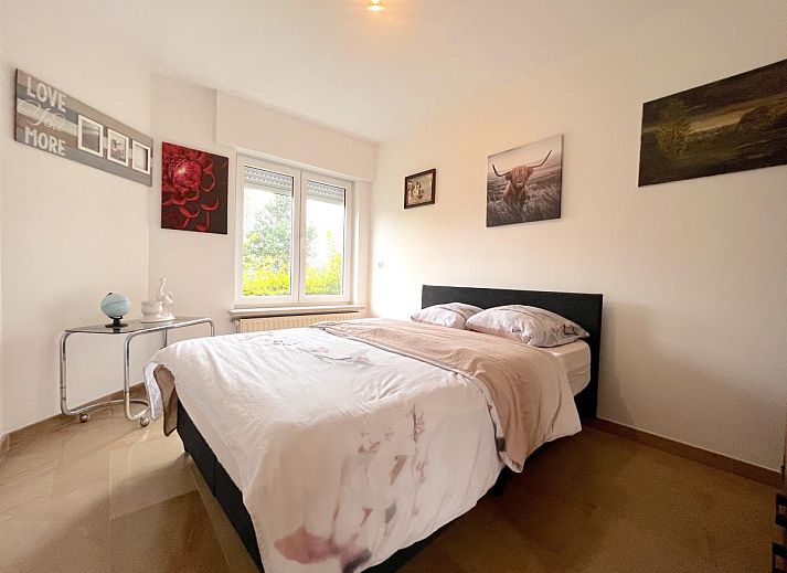 Gemuetliches Wohnzimmer im Ferienhaus Zingem mit grossen Fenstern und bequemen Sofas.