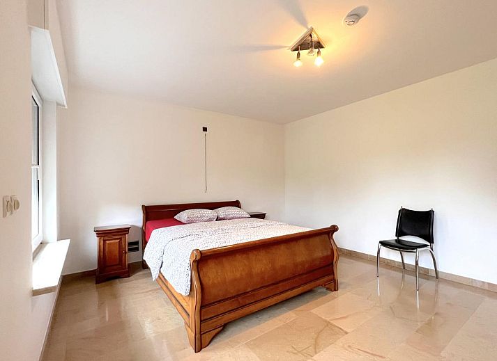 Esszimmer im Ferienhaus Zingem mit elegantem Kronleuchter und grossem Tisch.