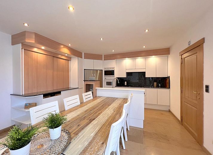 Esszimmer im Ferienhaus Zingem mit elegantem Kronleuchter und grossem Tisch.