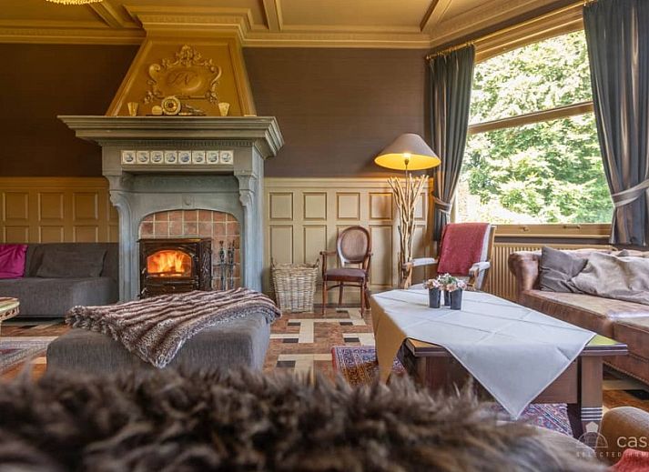 Gemuetliches Wohnzimmer im Ferienhaus Boeckhaege, Ronse, Ostflandern, mit Kamin und luxurioesem Kronleuchter.