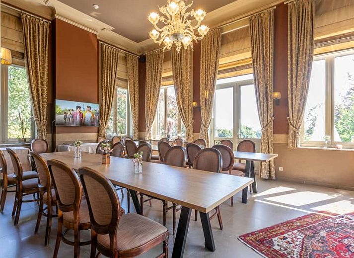 Gemuetliches Wohnzimmer im Ferienhaus Boeckhaege, Ronse, Ostflandern, mit Kamin und luxurioesem Kronleuchter.