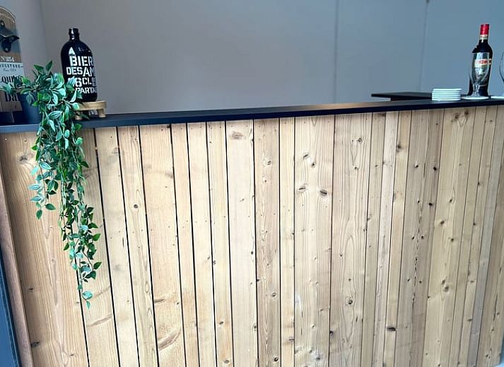 Gemuetliche Sitzecke im Ferienhaus in Merendree, Ostflandern, mit grossem Sofa und warmer Dekoration.