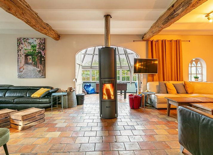 Gezellige woonkamer in vakantiehuis Alverwege, Merksplas, Antwerpen, met een warme haard en ruime zithoek voor ontspanning in een landelijke sfeer.