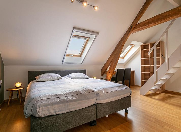 Gezellige eetruimte in vakantiehuis Alverwege, Merksplas, Antwerpen met rustieke houten balken en een ruime eettafel voor groepsdiners.