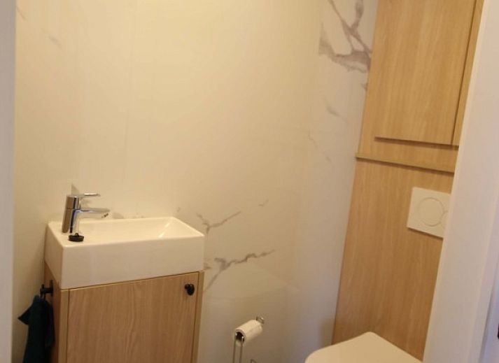 Geraeumiges Esszimmer im Huisje Nostalgie, Laakdal, Antwerpen, mit Holzmoebeln und moderner Beleuchtung.