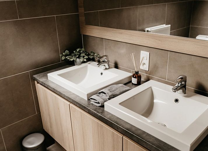 Modernes Badezimmer im Ferienhaus NatuRauw, Mol, Antwerpen, mit Holzschraenken und Doppelwaschbecken.