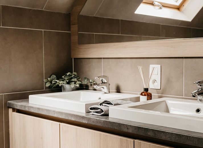 Modernes Badezimmer im Ferienhaus NatuRauw, Mol, Antwerpen, mit Holzschraenken und Doppelwaschbecken.