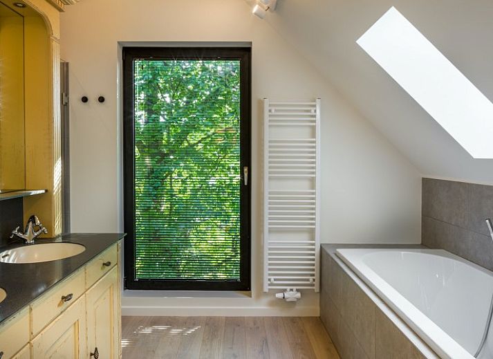 Ueberdachte Terrasse des Ferienhauses Mushoeve in Zoersel, Antwerpen, mit Esstisch aus Holz und Gartenblick.