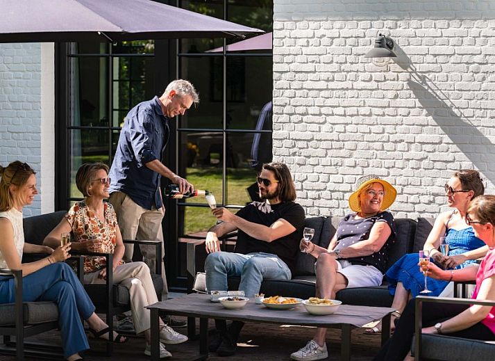 Ueberdachte Terrasse des Ferienhauses Mushoeve in Zoersel, Antwerpen, mit Esstisch aus Holz und Gartenblick.