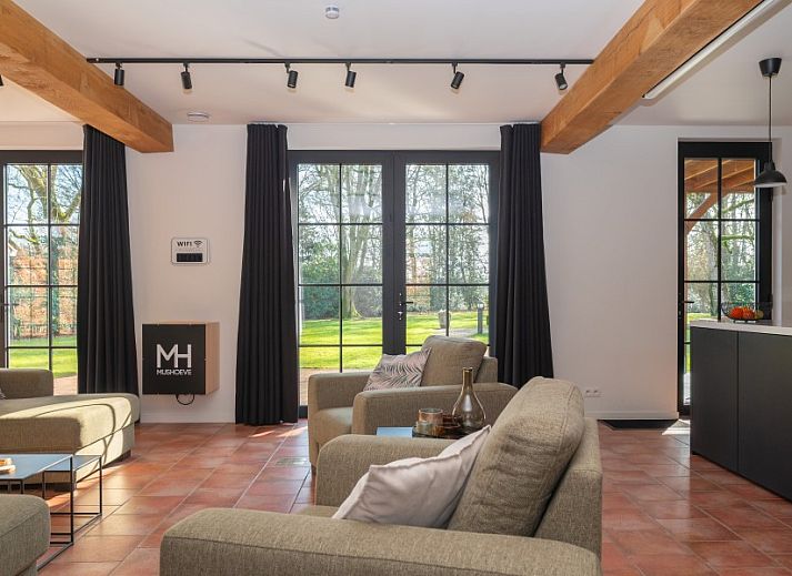 Gemuetliches Wohnzimmer von Mushoeve in Zoersel, Antwerpen mit Kamin und bequemen gelben Stuehlen.