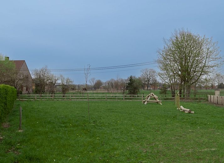Grote ramen in Nachteneel De Paardenstal, vakantiehuis in Ravels, Antwerpen, Belgie, bieden uitzicht op groene omgeving en kunst aan de muur.