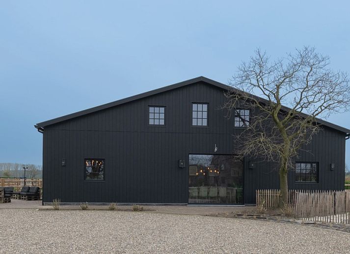 Grote ramen in Nachteneel De Paardenstal, vakantiehuis in Ravels, Antwerpen, Belgie, bieden uitzicht op groene omgeving en kunst aan de muur.