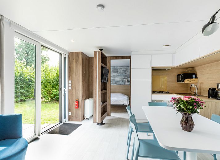 Modernes Interieur des Taos XL Delux Ferienhauses in Turnhout, Antwerpen mit heller Kueche und Blick auf den gruenen Garten.