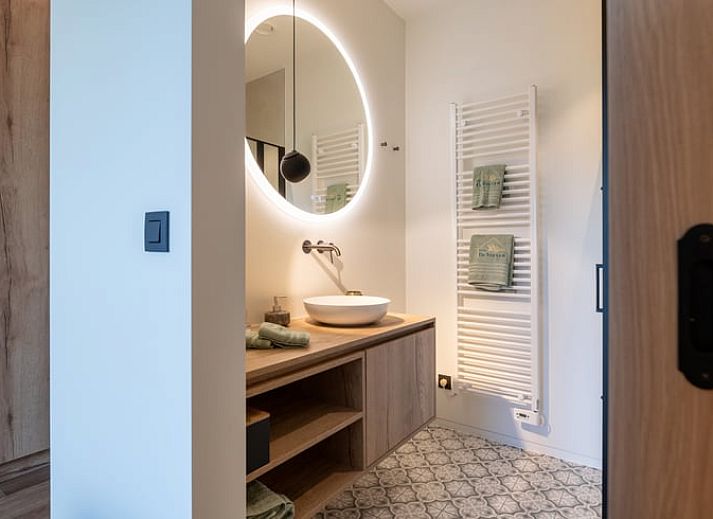 Ferienhaus in Kasterlee, Antwerpen, Belgien, attraktiv beleuchtet in der Abenddaemmerung mit Holzfassade und umgebender Natur.