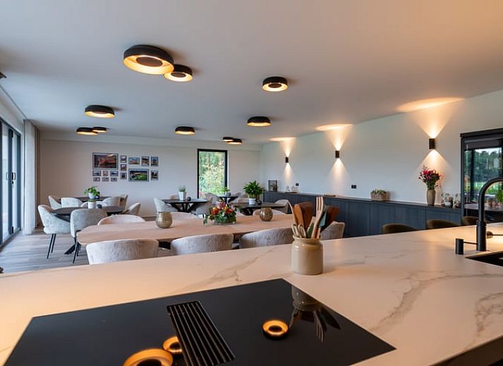 Ferienhaus in Kasterlee, Antwerpen, Belgien, attraktiv beleuchtet in der Abenddaemmerung mit Holzfassade und umgebender Natur.