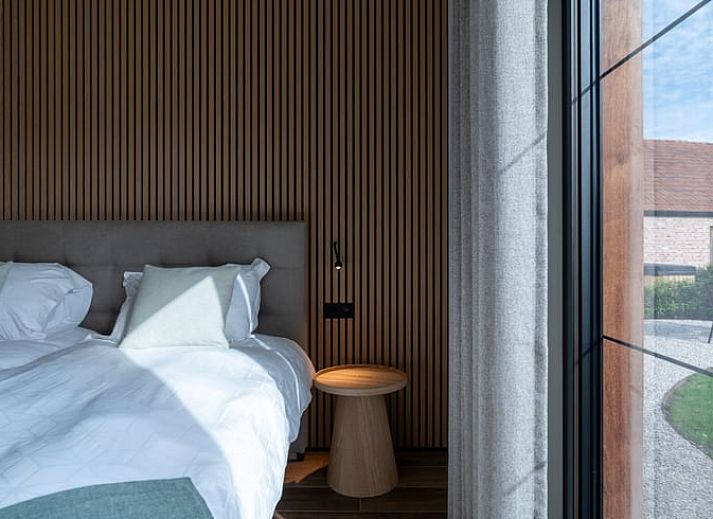 Ferienhaus in Kasterlee, Antwerpen, Belgien, attraktiv beleuchtet in der Abenddaemmerung mit Holzfassade und umgebender Natur.